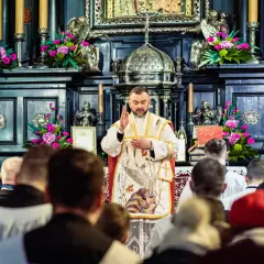 Kapłan w kościele, przed ołtarzem z kwiatami, błogosławi wiernych. W tle widać ozdobne zdobienia i świece. Jasna Góra intencje mszalne.