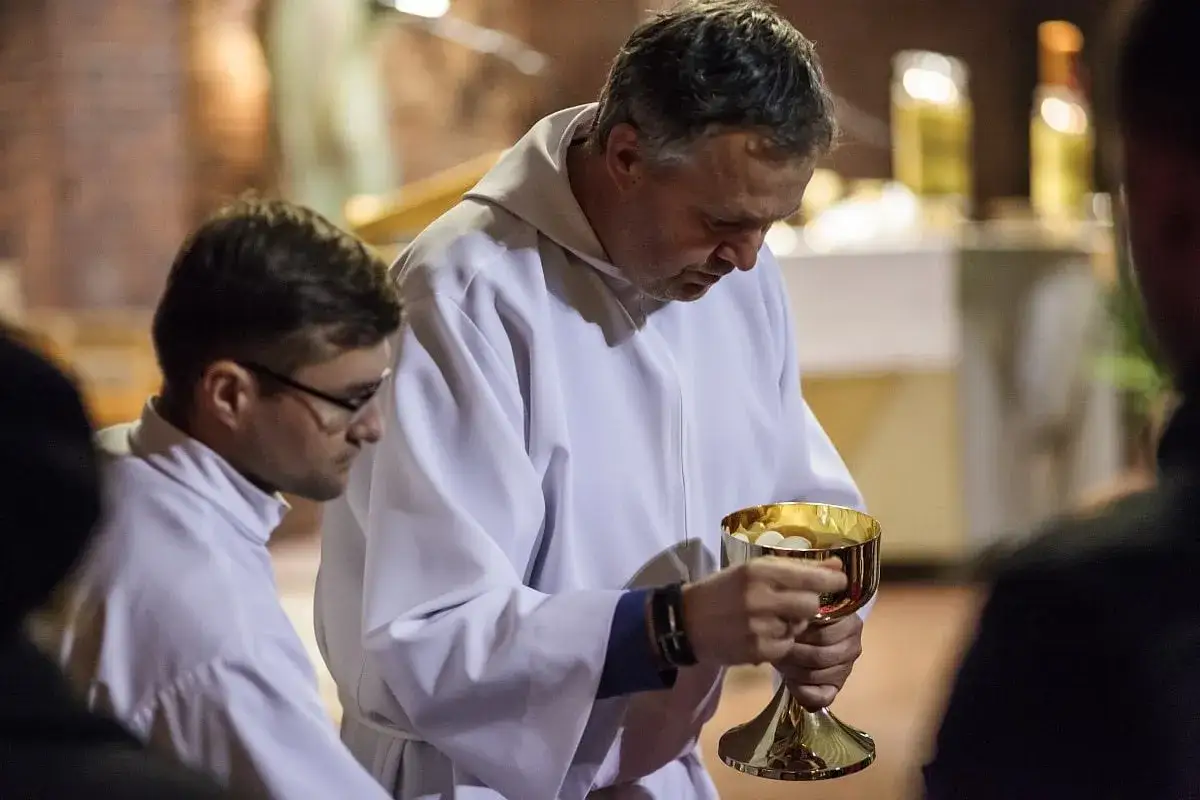 Kapłan z kielichem pełnym hostii podczas post eucharystyczny. Grzech ciężki nie przeszkadza w tej chwili.