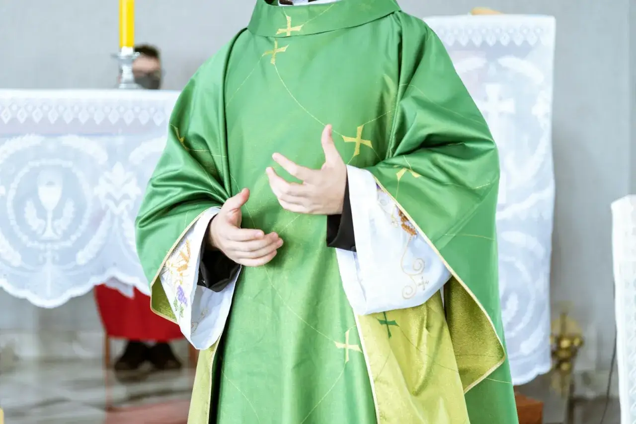 Kapłan w zielonej szacie z krzyżami, gestykuluje, jakby tłumaczył różnicę między grzechem ciężkim a lekkim.