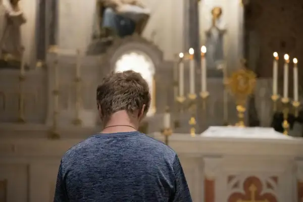 Młody mężczyzna w kościele, zadumany nad tym, czy z masturbacji trzeba się spowiadać.