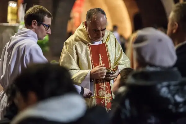 Kapłan udziela Komunii Świętej. Wierni przyjmują Ciało Chrystusa, co jest ważnym momentem po spowiedzi, gdy grzech ciężki został wyznany.