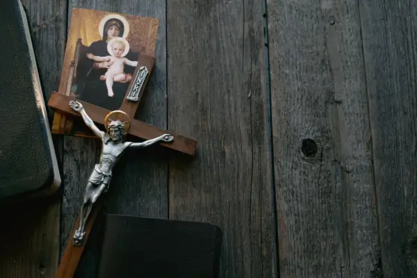 Krzyż z Jezusem, obraz Matki Boskiej i Biblia na drewnianym tle. Symbolika odkupienia i wiecznej kary za grzechy.